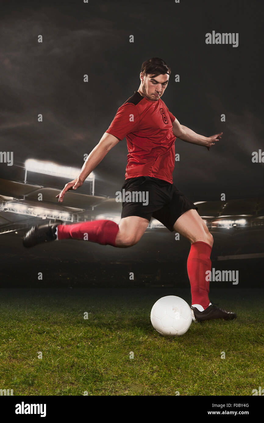 Voller Länge des jungen Fußballer treten Ball auf Feld Stockfoto