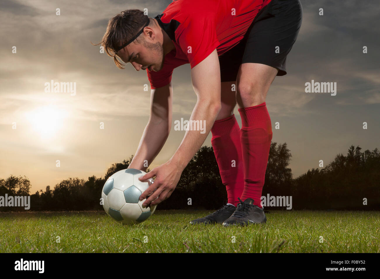 Voller Länge des jungen Fußballer Ball auf Feld positionieren Stockfoto