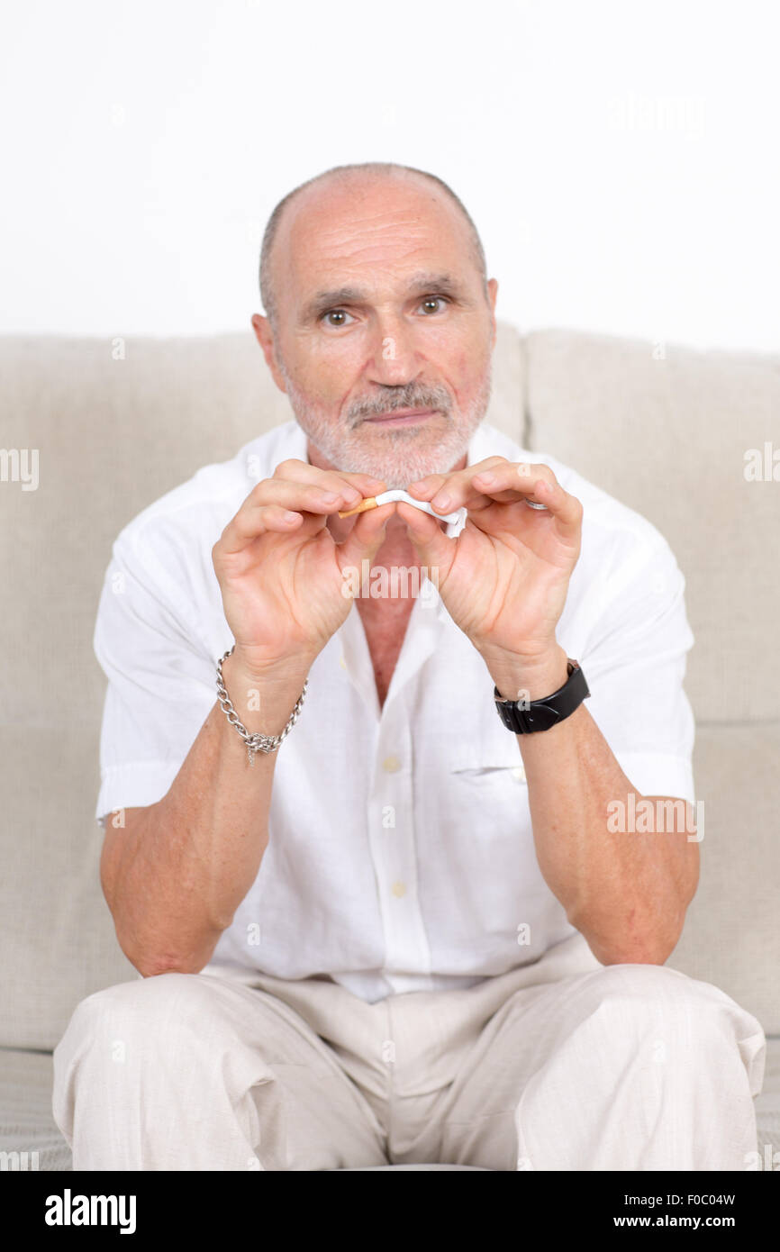 Älterer Mann bricht eine Zigarette als Symbolbild Quiting Rauchen Stockfoto