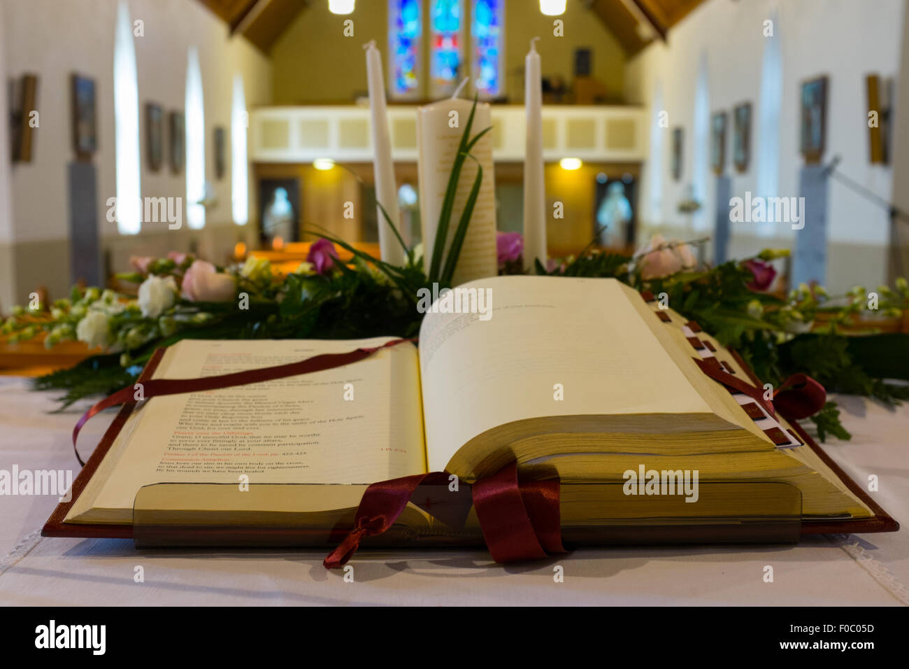 Aufgeschlagene Bibel und Hochzeitsblumen auf dem Altar in der katholischen Kirche. Flachen DOF Stockfoto