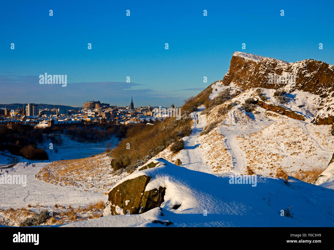 Schnee bedeckt die Salisbury Crags Edinburgh Castle im Hintergrund Scotland UK Stockfoto