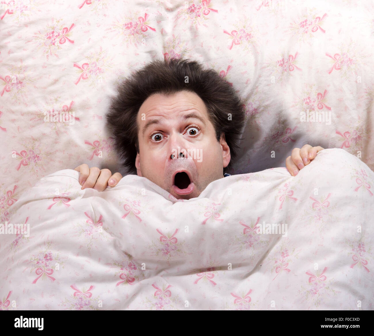 erschrocken Mann im Bett liegend Stockfoto