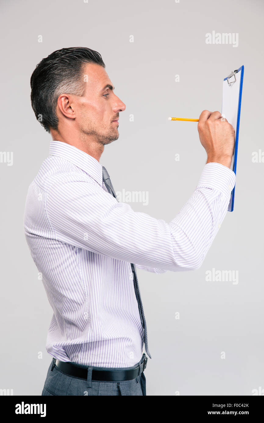 Seite Ansicht Porträt eines Geschäftsmannes Schreiben von Notizen in Zwischenablage isoliert auf aw Hite background Stockfoto