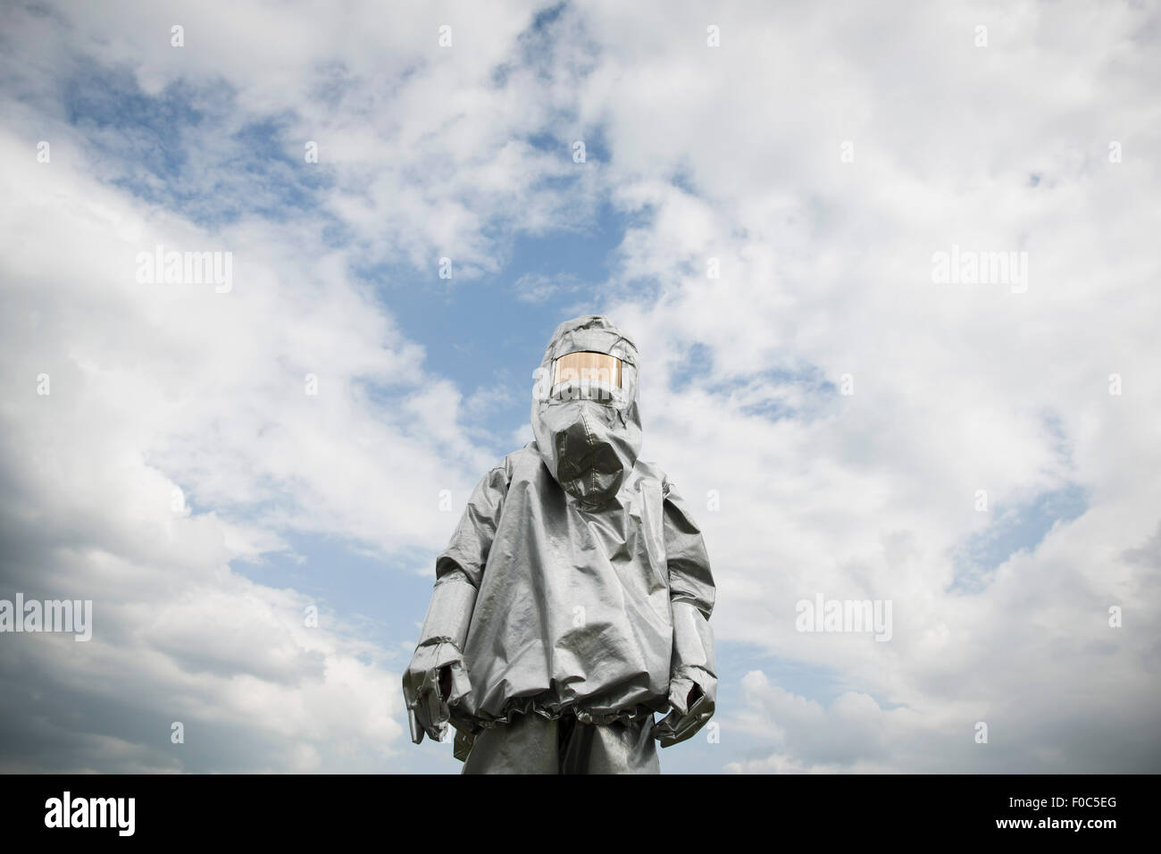 Eine Person in einem Strahlung Schutzanzug steht vor einem bewölkten Himmel Stockfoto
