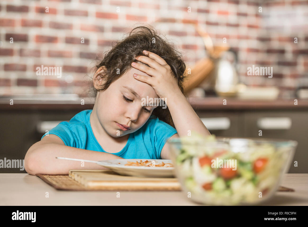 Trauriges Mädchen mit Kopf in der Hand beim Frühstück am Tisch Stockfoto