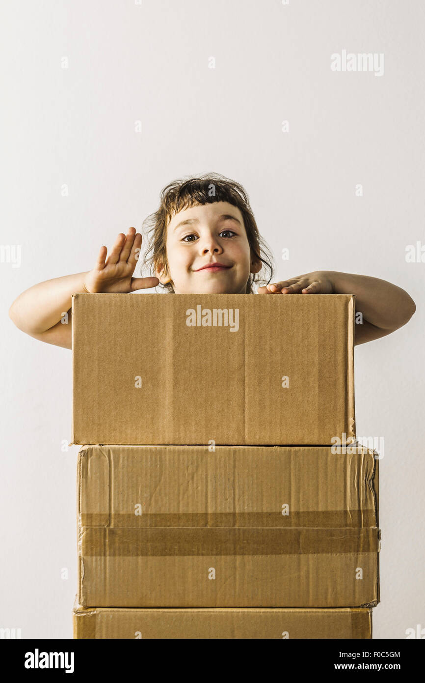 Porträt von glücklichen Mädchen stehend hinter gestapelten Kisten Antippen Stockfoto