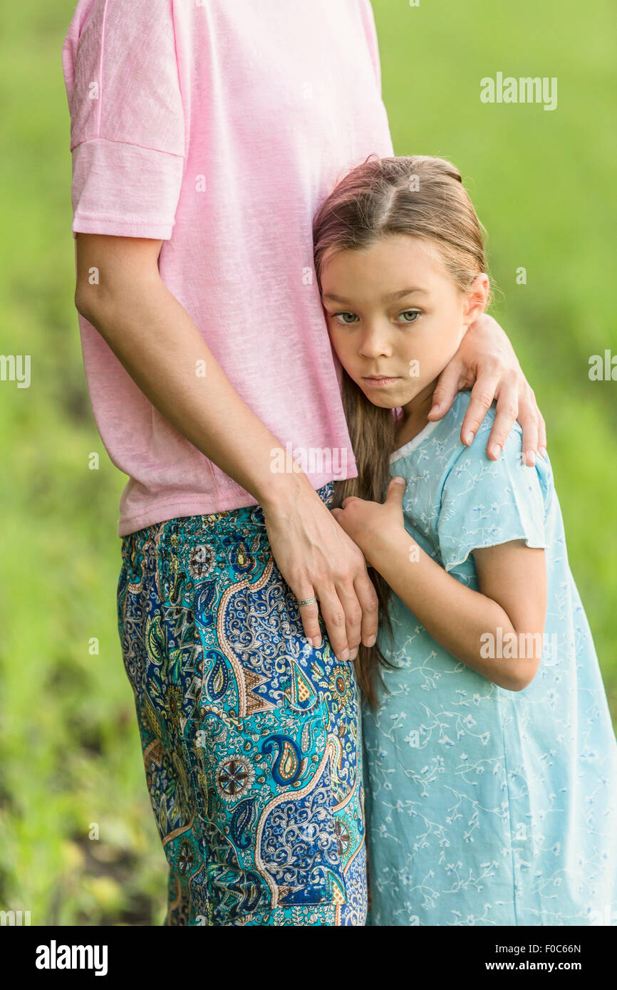 Trauriges Mädchen umarmt Mutter auf Feld Stockfoto