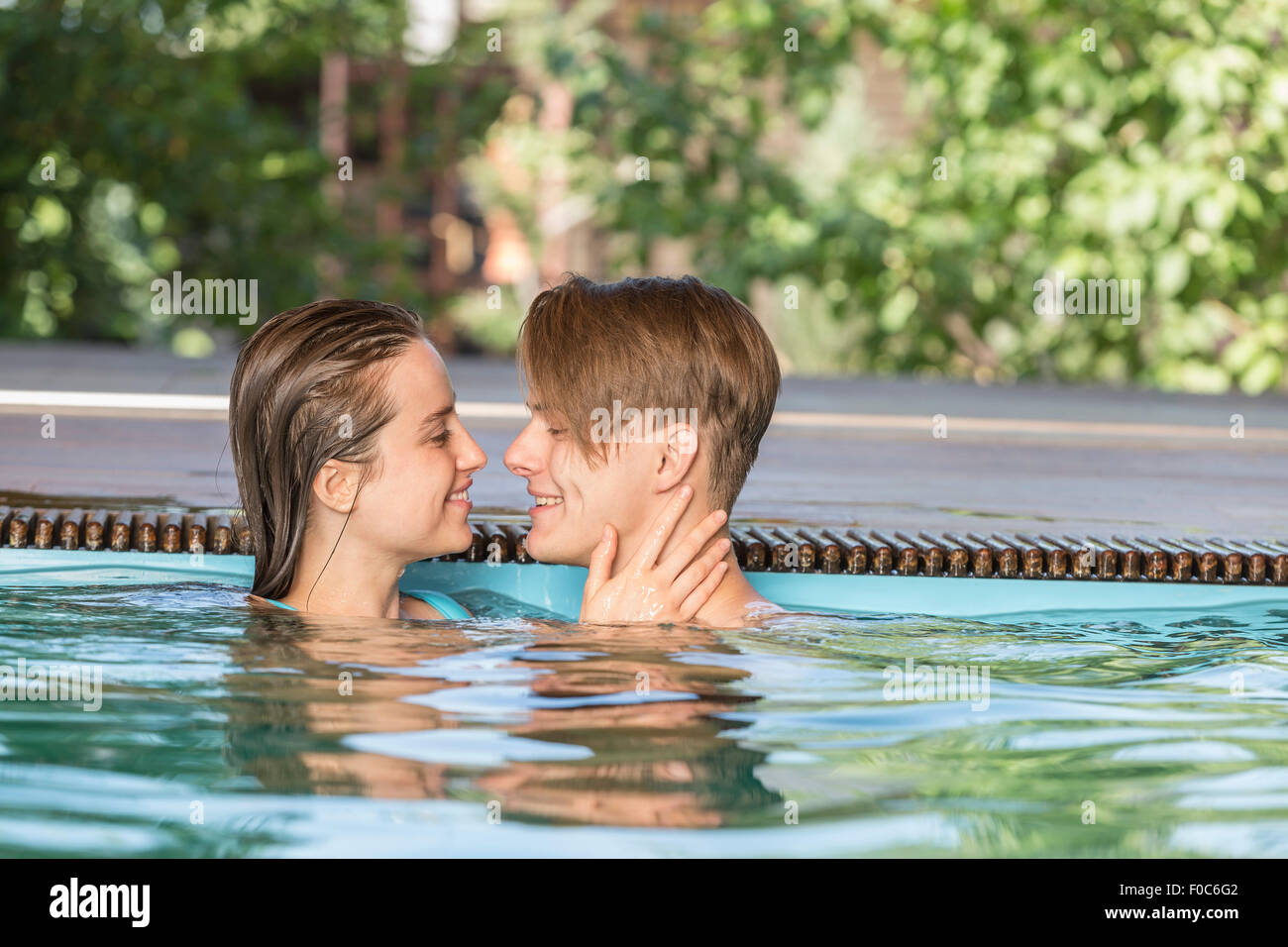 Seitenansicht der leidenschaftliche Paare lächelnd in Schwimmbad Stockfoto