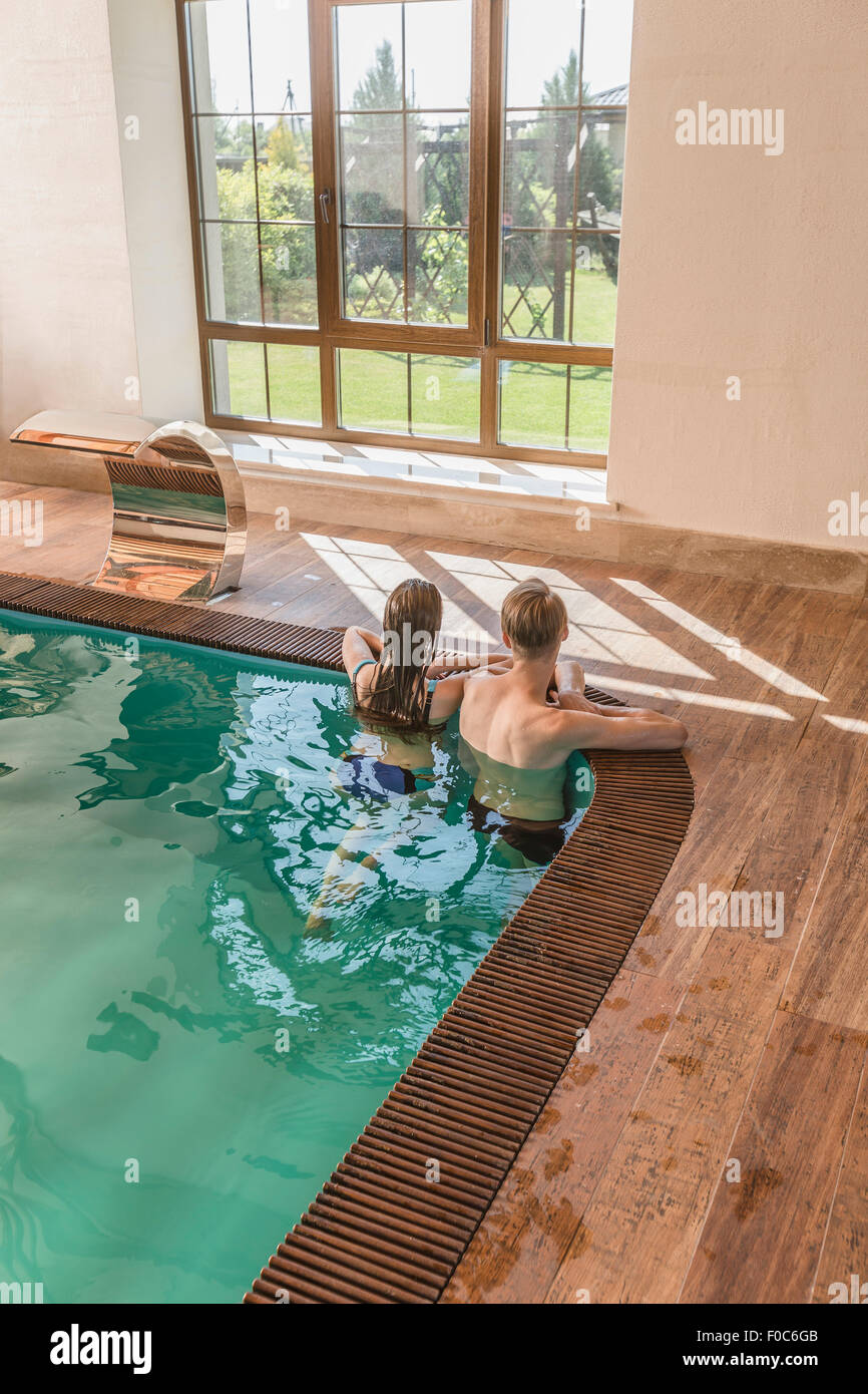 Rückansicht des entspannenden junges Paar am Rande von Schwimmbad Stockfoto