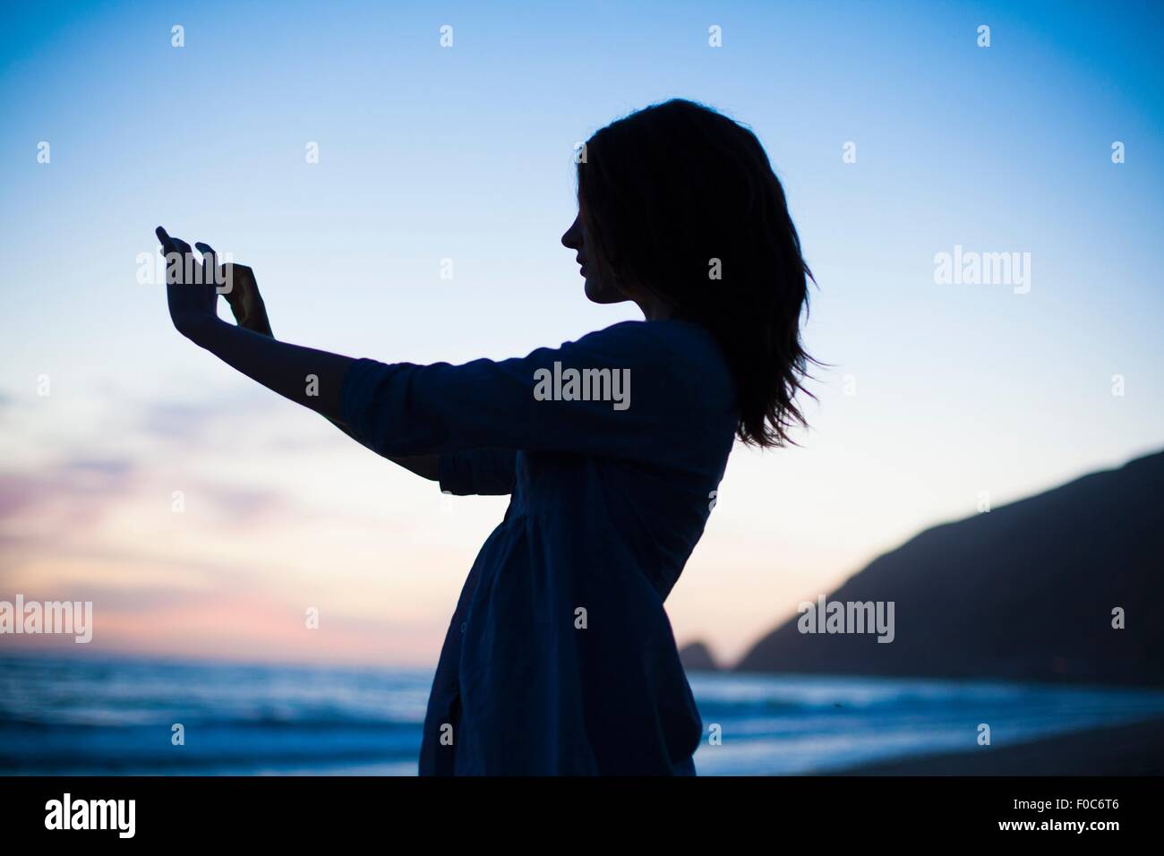 Frau, die Selfie am Strand bei Sonnenuntergang, Malibu, Kalifornien, USA Stockfoto