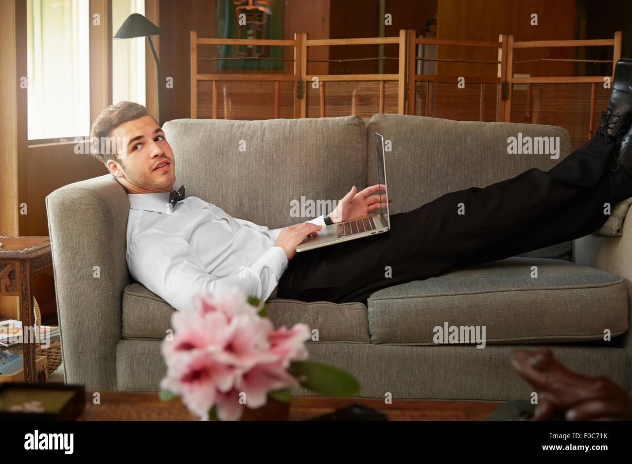 Porträt des Mannes intelligente Kleidung für die Verlegung auf Sofa mit laptop Stockfoto