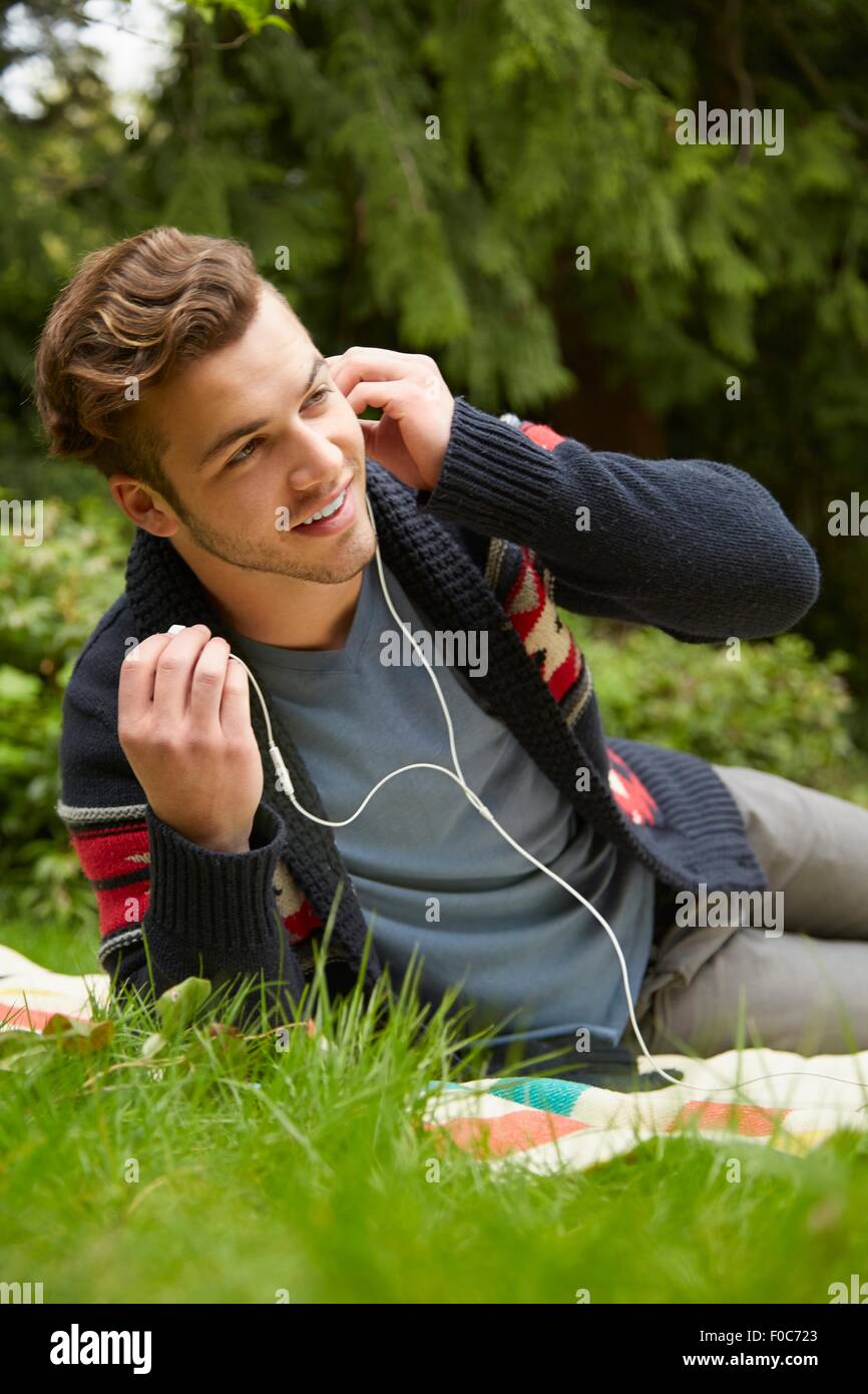 Porträt des Mannes verlegen im Garten hören auf Smartphone trägt Kopfhörer Stockfoto
