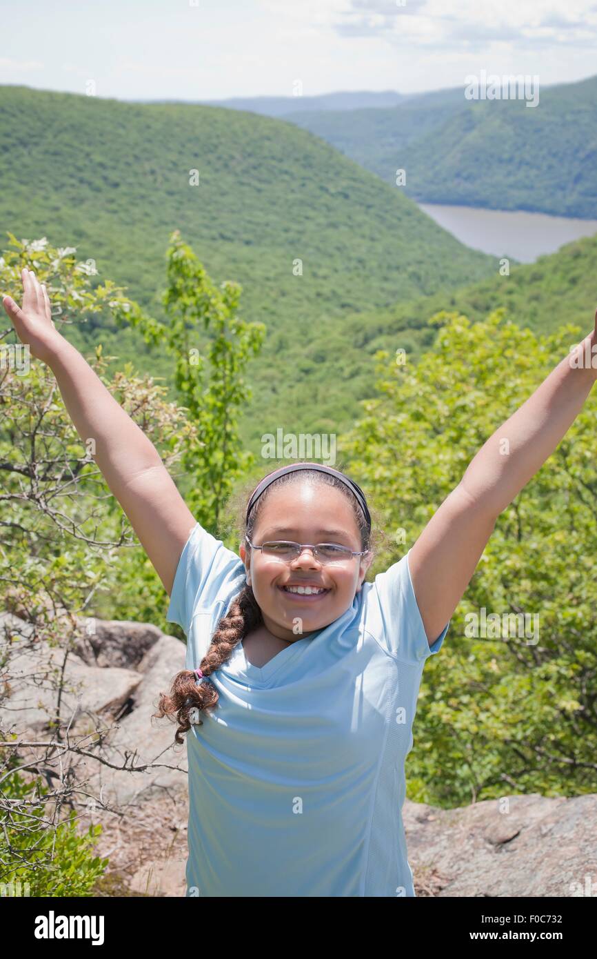 Junges Mädchen an Spitze der Hügellandschaft, Arme heben, Lächeln Stockfoto