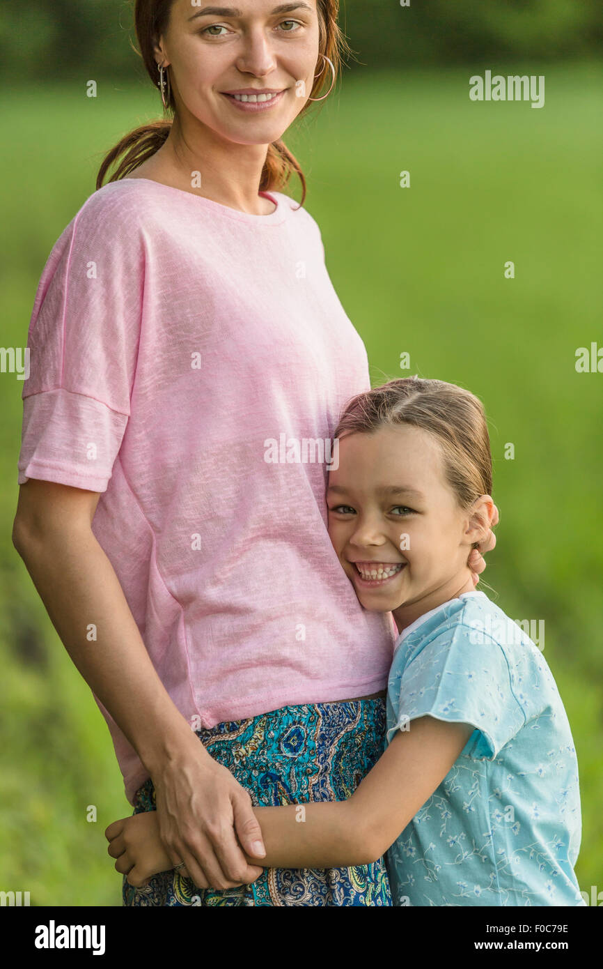 Porträt von lächelndes Mädchen umarmt Mutter auf Feld Stockfoto