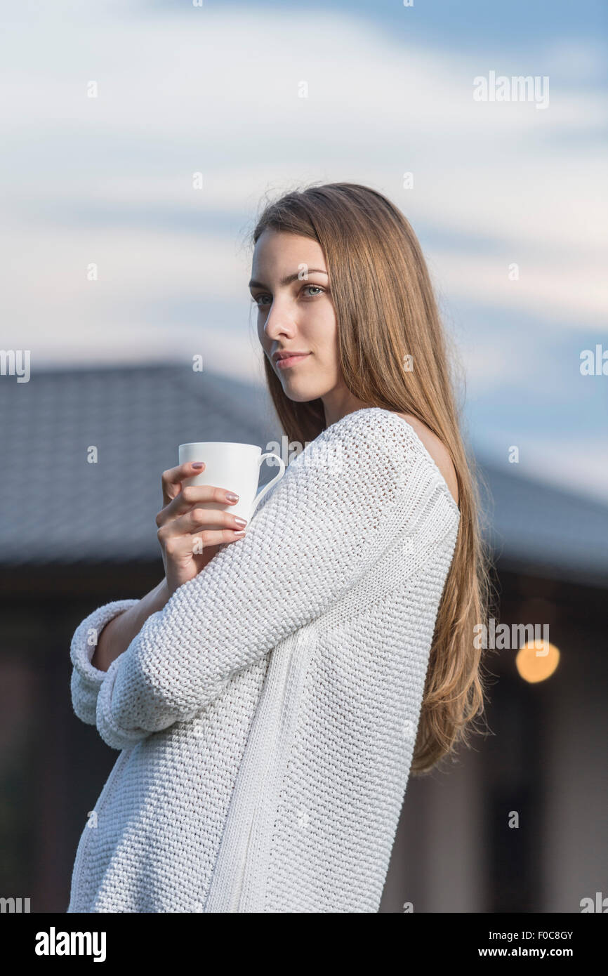 Schöne junge Frau, die Kaffeetasse im Freien halten Stockfoto