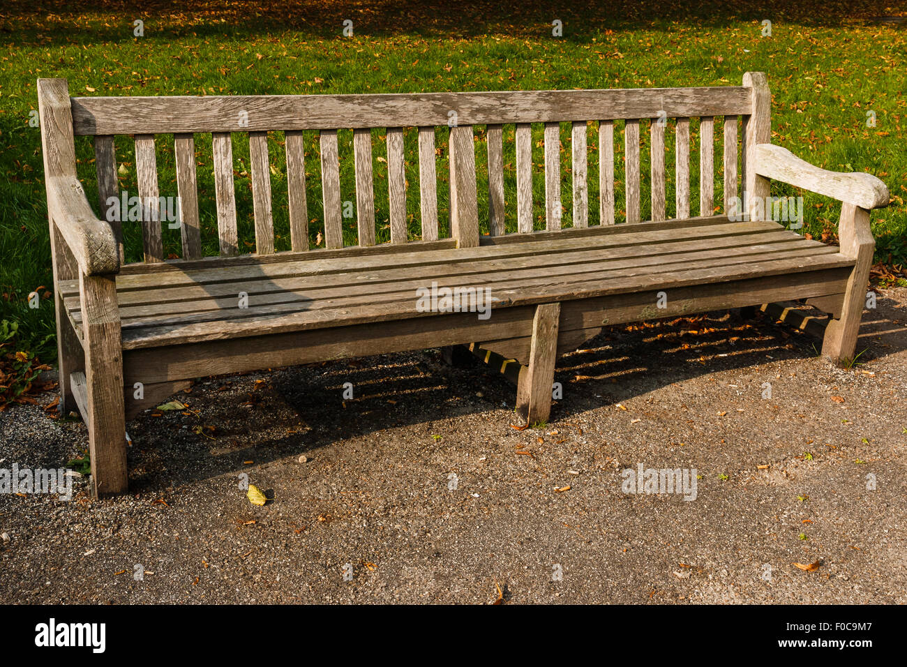 Holzbank im Park leer ist. Verwittertes Aussehen. Sonne scheint Stockfoto