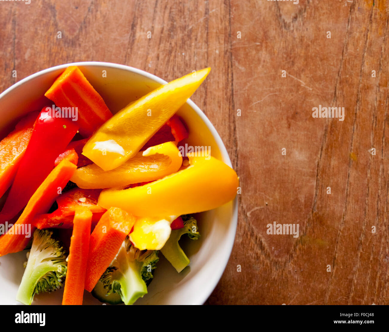 Eine Schale mit buntem Gemüse auf einem Holztisch Stockfoto