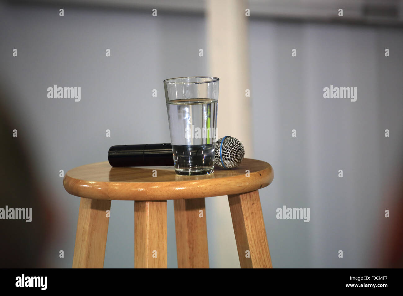 Mikrofon und Glas Wasser warten auf einem Hocker für eine Person zu sprechen Stockfoto