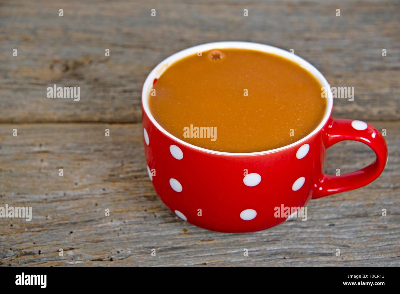 Tomatensuppe in einem roten Suppe-Becher mit weißen Tupfen auf rustikalen Holz. Stockfoto