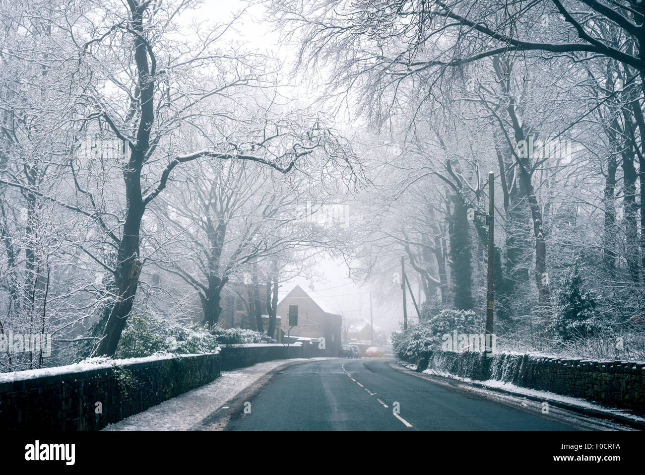 Straße führt nach einem Häuschen bedeckt in den Schnee in britische Landschaft. Stockfoto