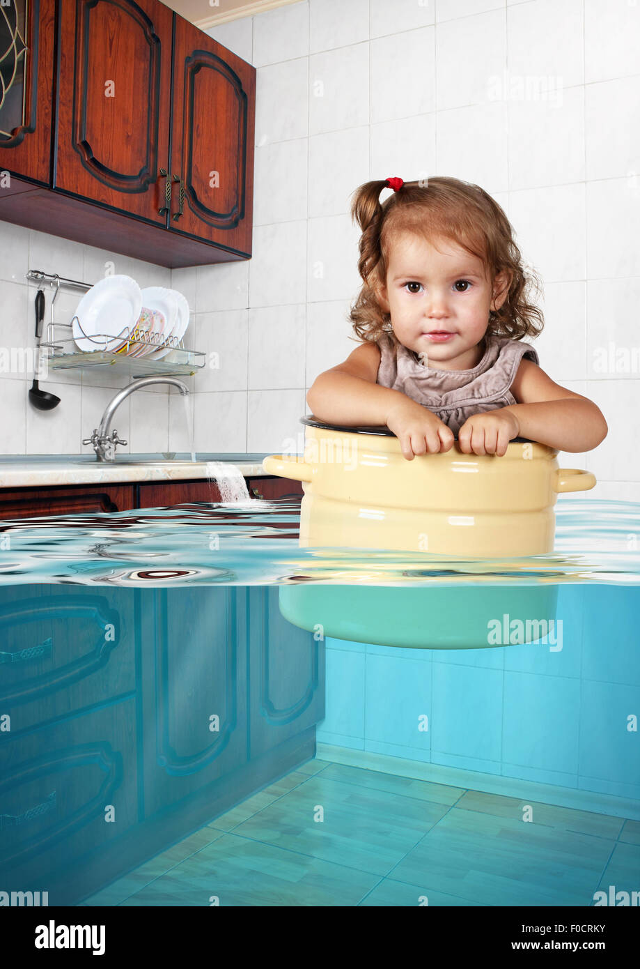 Lustiges kleines Kind schwimmen in Pfanne in der gefluteten Küche durcheinander Kreativkonzept Stockfoto