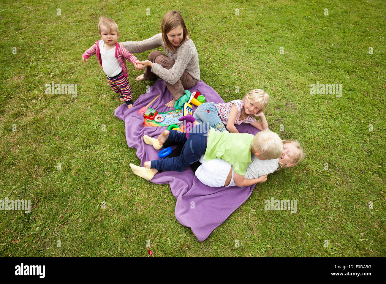 Kinder spielen zusammen mit einer jungen Mutter Stockfoto