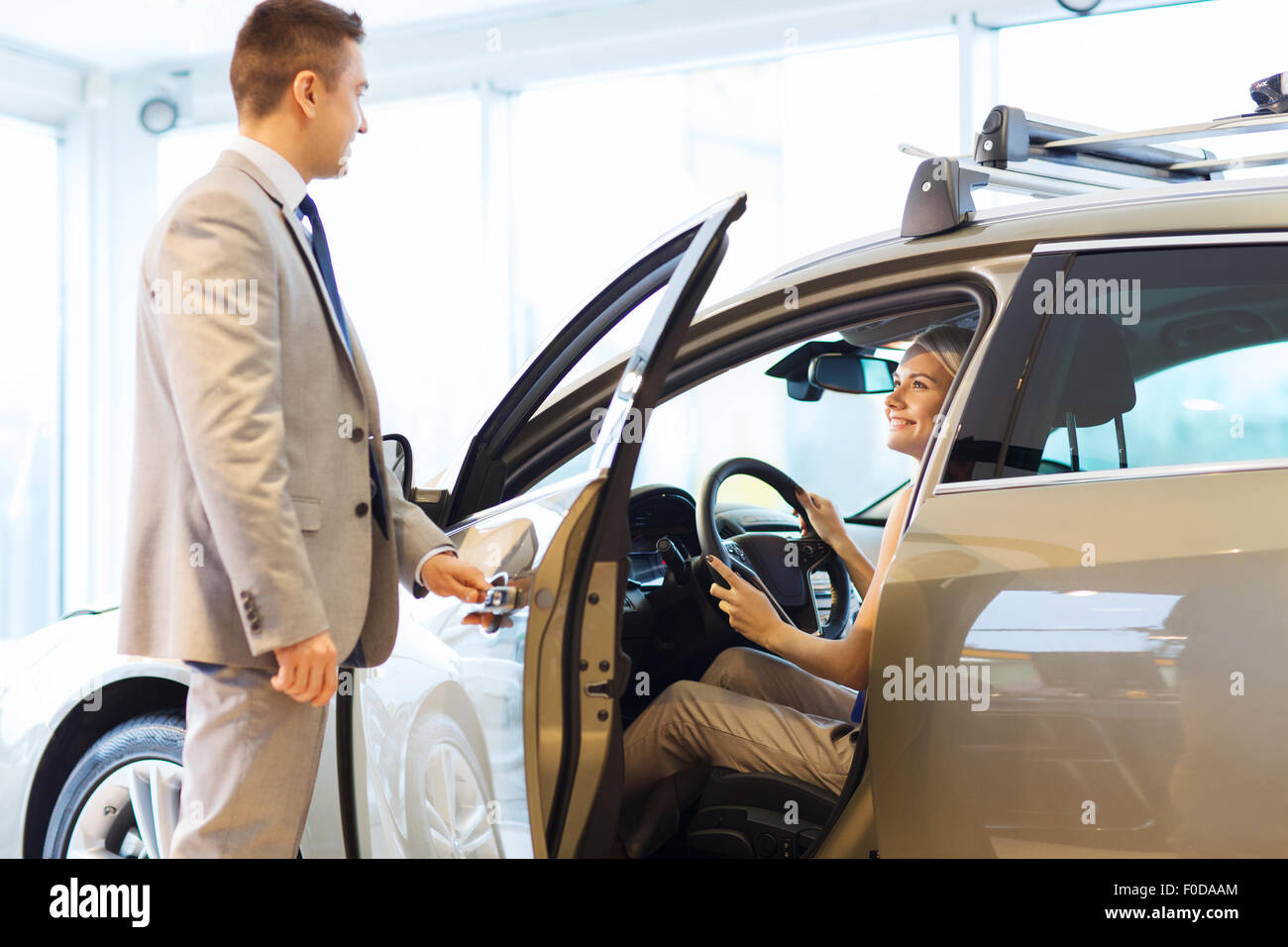 glückliche Frau mit Autohändler in Automesse oder salon Stockfoto