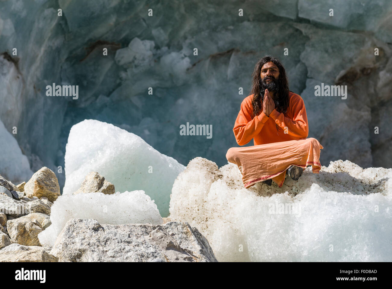 Ein Sadhu, heiliger Mann, sitzt und in Lotus Pose, Padmasana, auf einem Eisblock am Gaumukh, die wichtigste Quelle des Heiligen Geistes zu beten Stockfoto