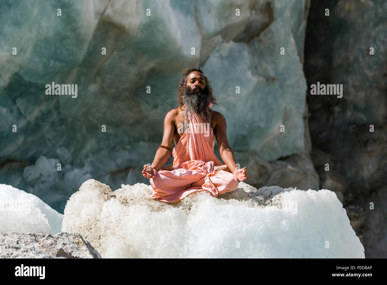 Ein Sadhu, heiliger Mann, sitzt und meditiert in Lotus-Pose, Padmasana, auf einem Eisblock am Gaumukh, die wichtigste Quelle des Heiligen Stockfoto