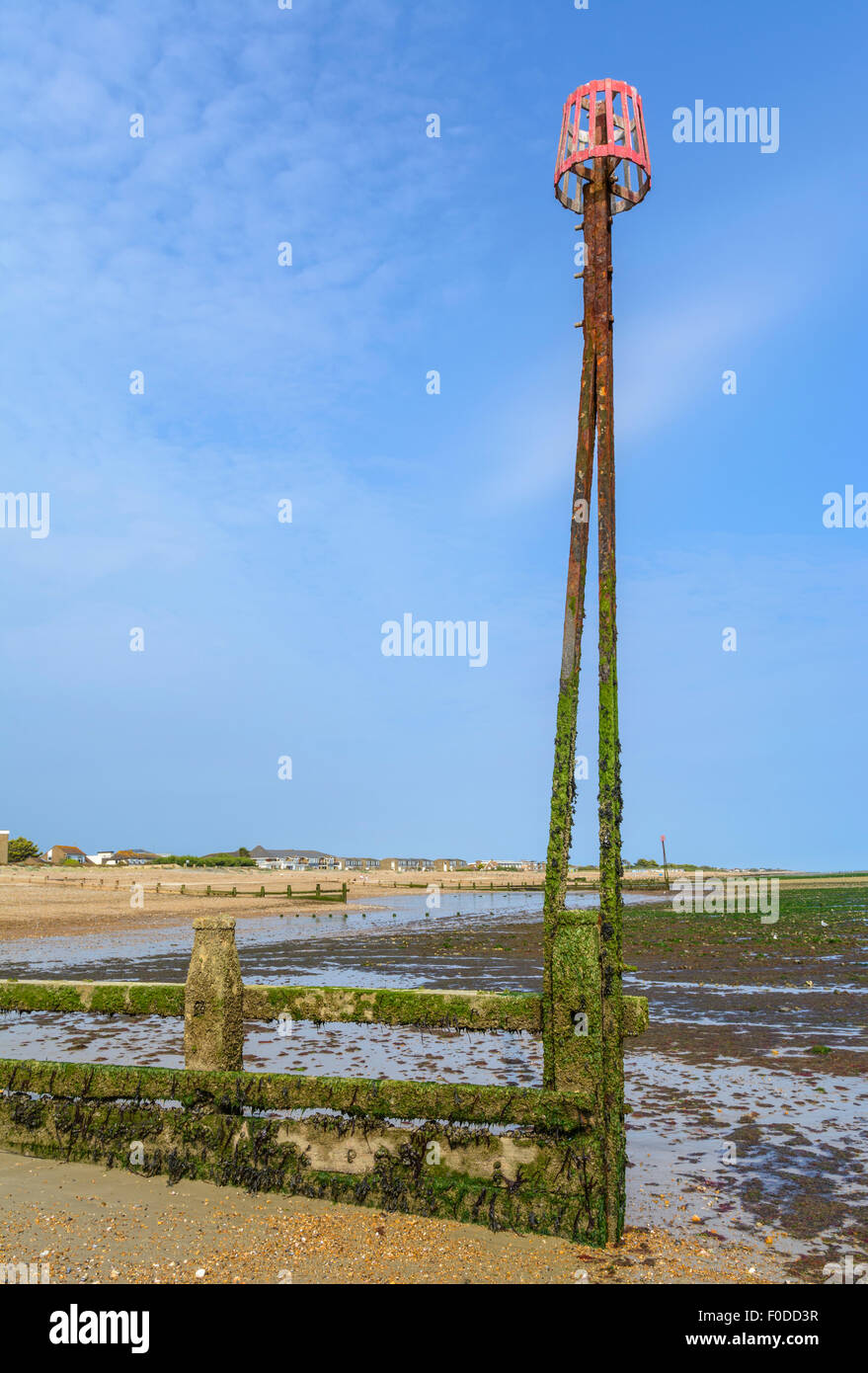 Gezeiten Sie Marker am Meer am Ende einer Buhne am Strand, bei Ebbe, gegen blauen Himmel, im Vereinigten Königreich. Stockfoto
