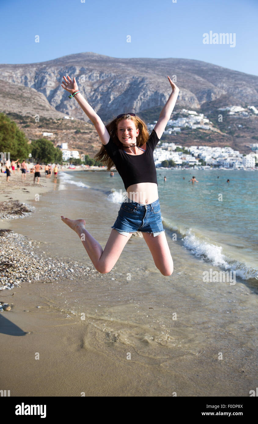 Junges Mädchen springt vor Freude am Strand bei der Ankunft für ihren Sommerurlaub Stockfoto