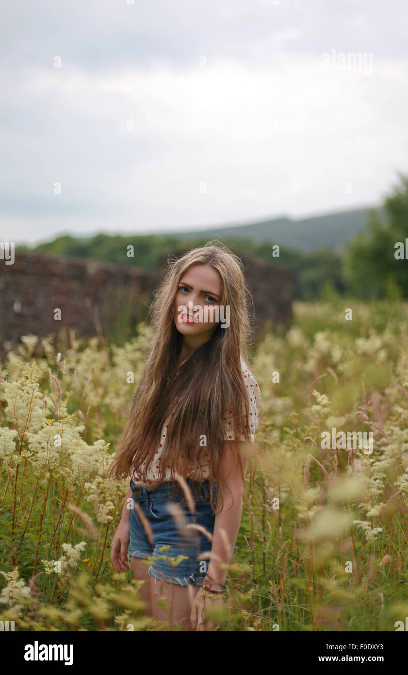 Schöne Teenager Girlwith lange braune Haare stehen in einem Feld von Blumen. Stockfoto