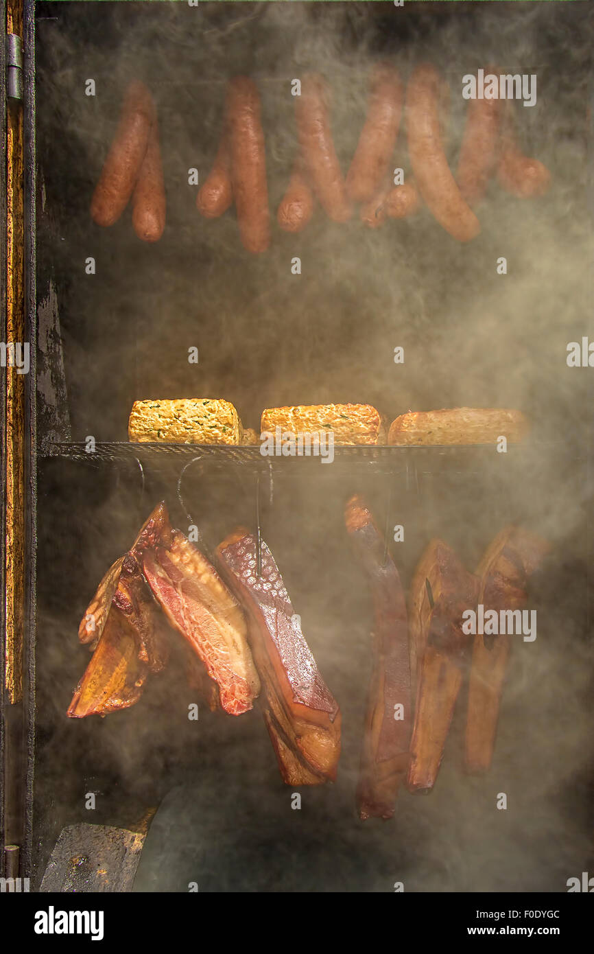 Mais, hausgemachte Wurst, Käse und Schinken im Barbecue-Smoker. Stockfoto