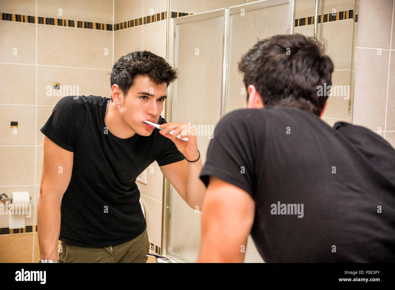 Kopfschuss attraktive junge Mann Zähneputzen mit Zahnbürste, selbst im Spiegel betrachten Stockfoto