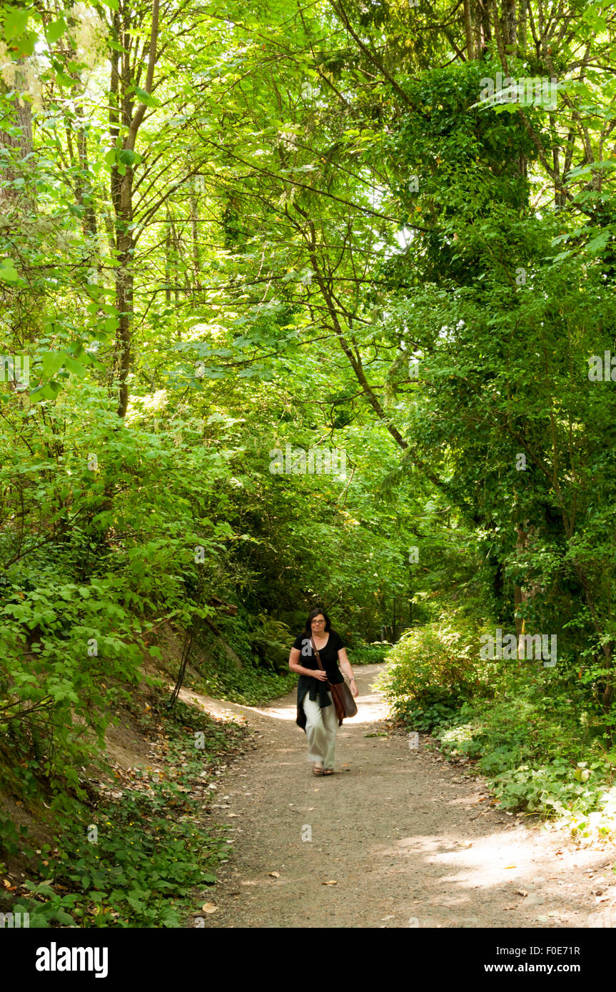 Eine Frau zu Fuß durch einen der Pfade des Lincoln Park in West Seattle. Stockfoto