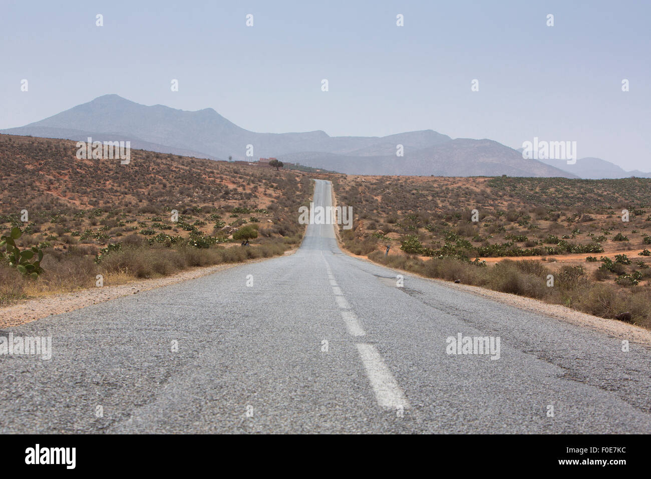 Geradeaus durch die Wüste in der Region von Tata, Berge im Hintergrund. Marokko, Afrika Stockfoto