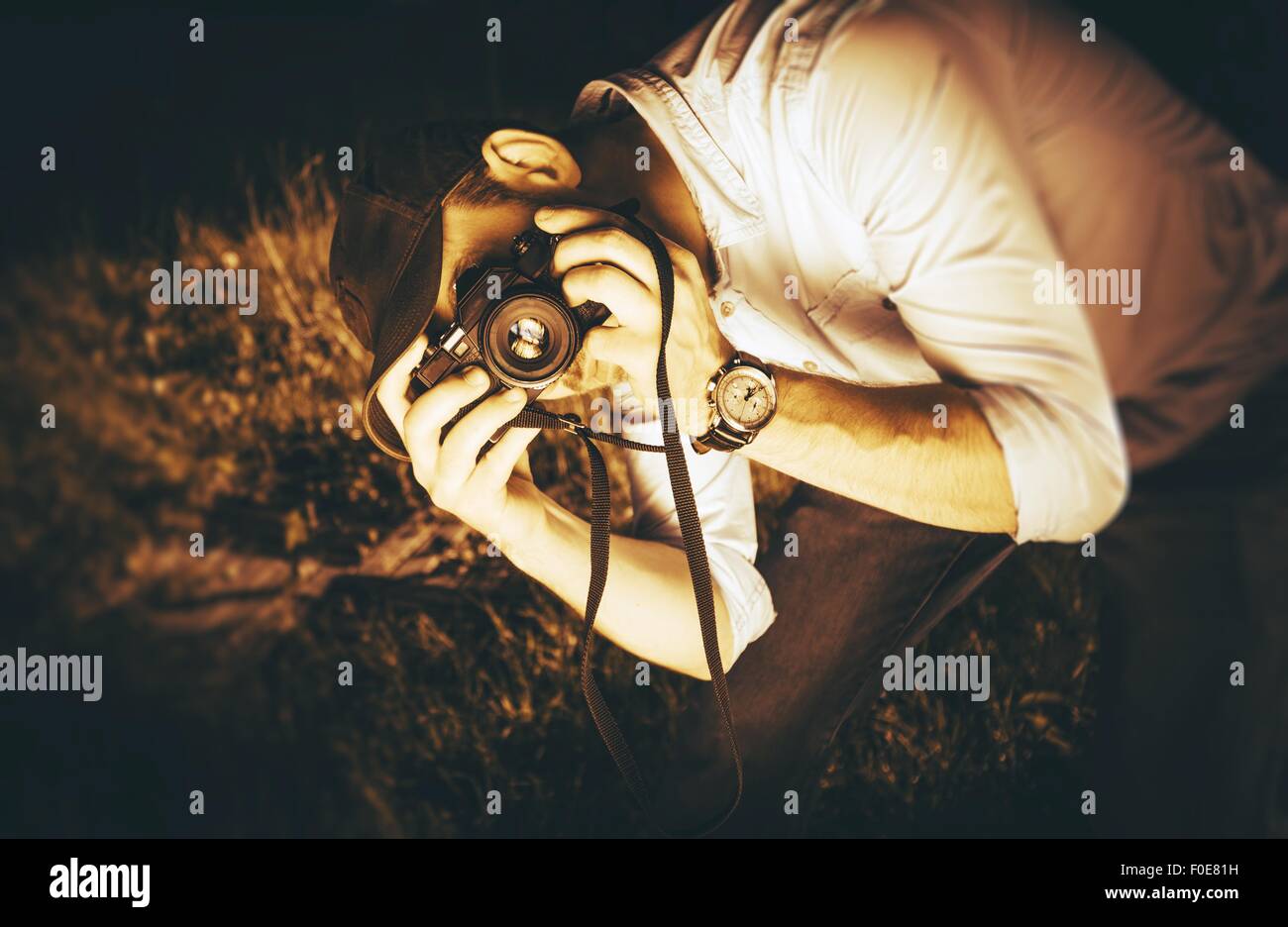 Fotograf in Aktion. Kaukasischen Männchen mit Vintage Analog-Kamera fotografieren. Sepia Verschneidung Fotografie Farbkonzept. Stockfoto