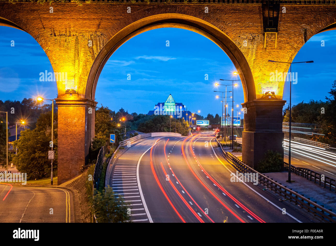 Eisenbahn-Viadukt überqueren M60 Autobahn in der Nähe von Manchester, UK. Tail Lichter der Autos verlassen Trail Unterquerung der Brücke. Stockfoto