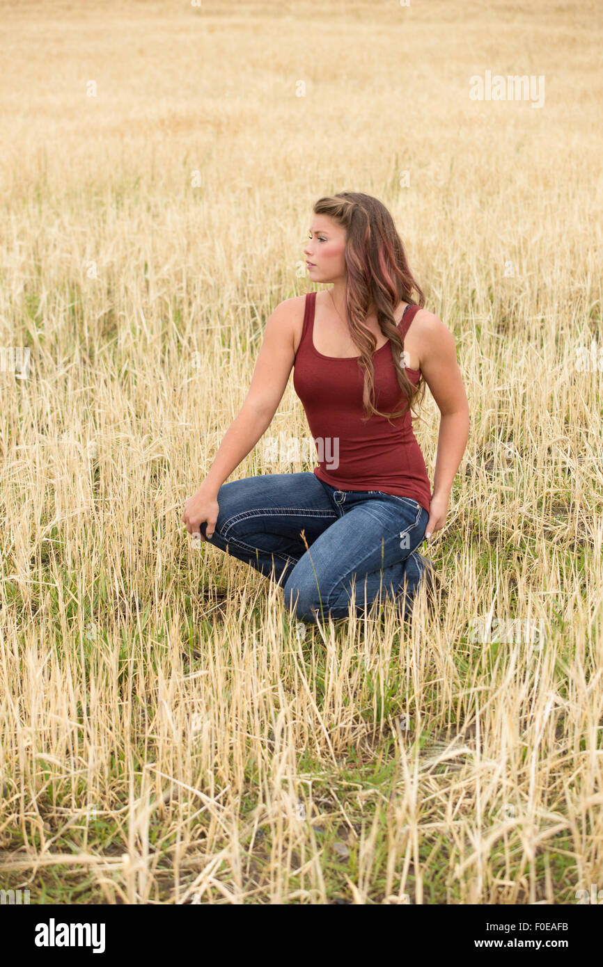 Junge Frau posiert in großen Weizen Feld tragen rote Tanktop und Jeans. Stockfoto