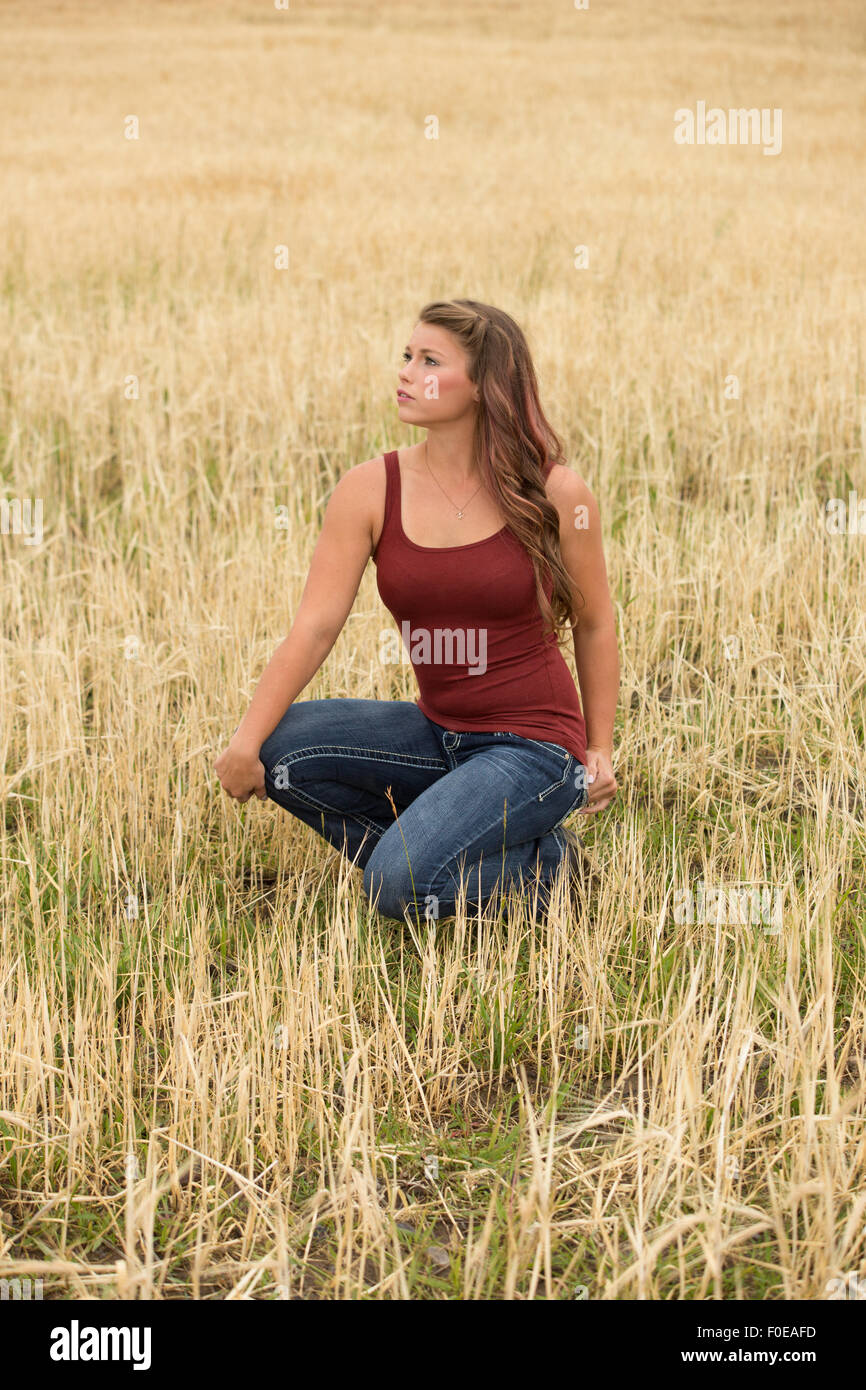 Junge Frau posiert in großen Weizen Feld tragen rote Tanktop und Jeans. Stockfoto