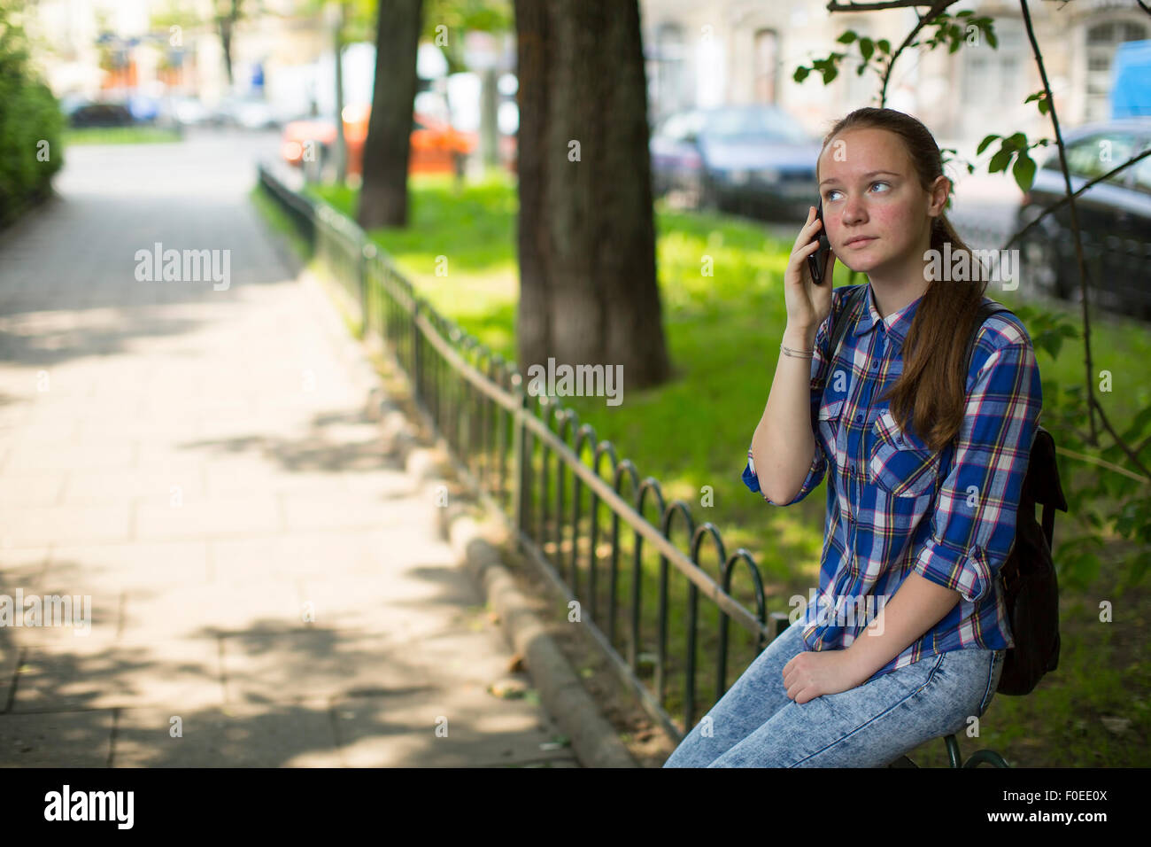 Teenager-Mädchen sehnsüchtig auf dem Handy beim Sitzen im freien sprechen. Stockfoto