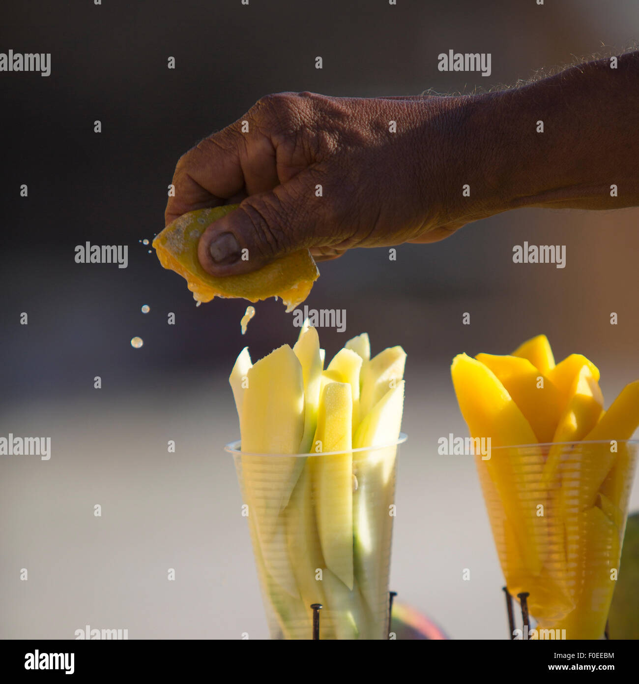 Hand drückte einen gelben Zitrusfrüchten über Stücke Melone in Cartagena/Kolumbien 2014. Stockfoto