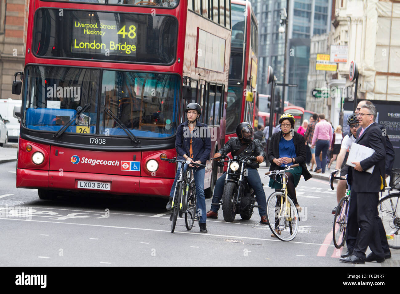 Weiblichen London Radfahrer an der Ampel im morgendlichen Berufsverkehr mit Postkutsche bus Stockfoto