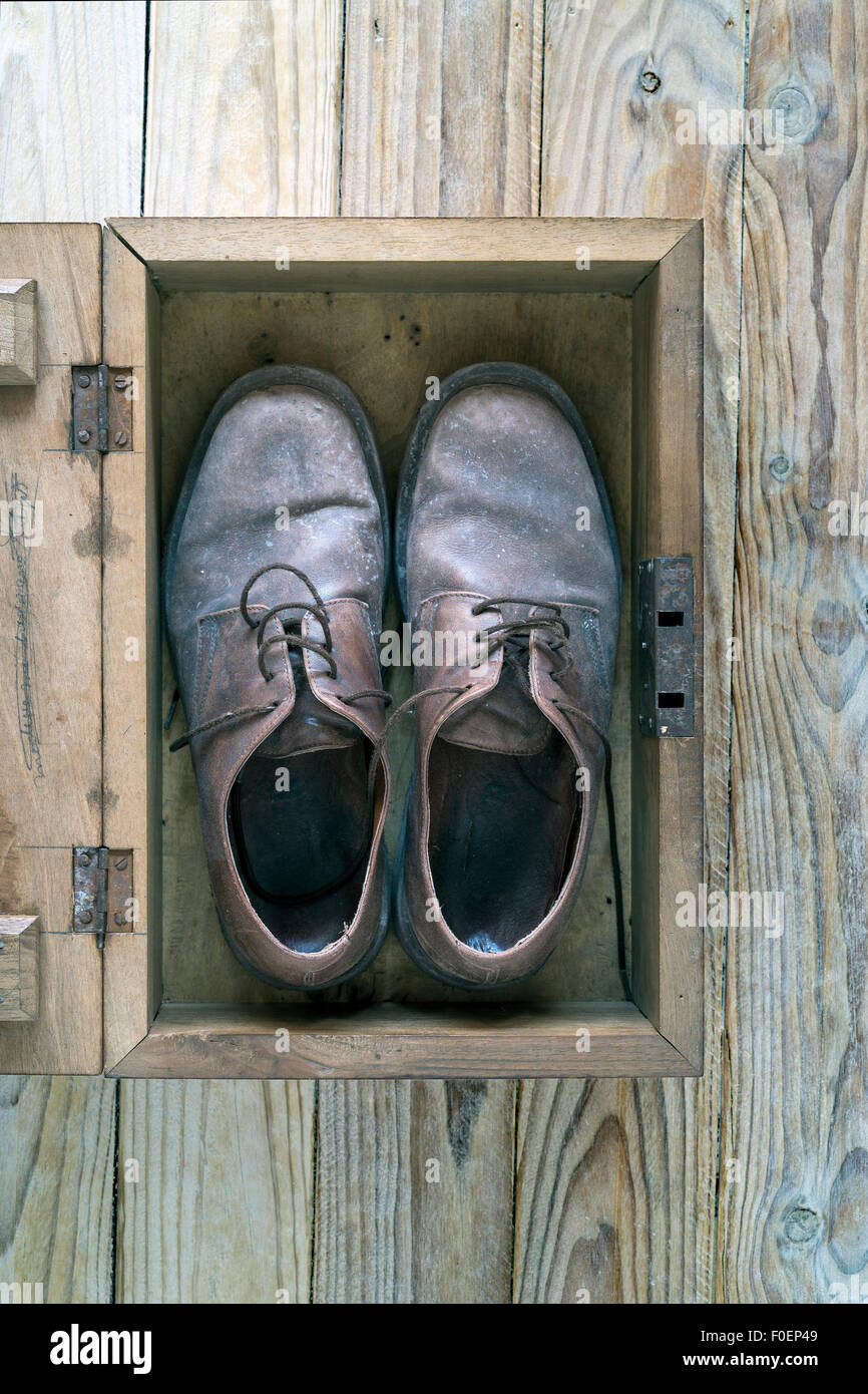Eine Holzkiste, mit ein paar alte, abgenutzte Schuhe auf einem hölzernen Hintergrund Stockfoto