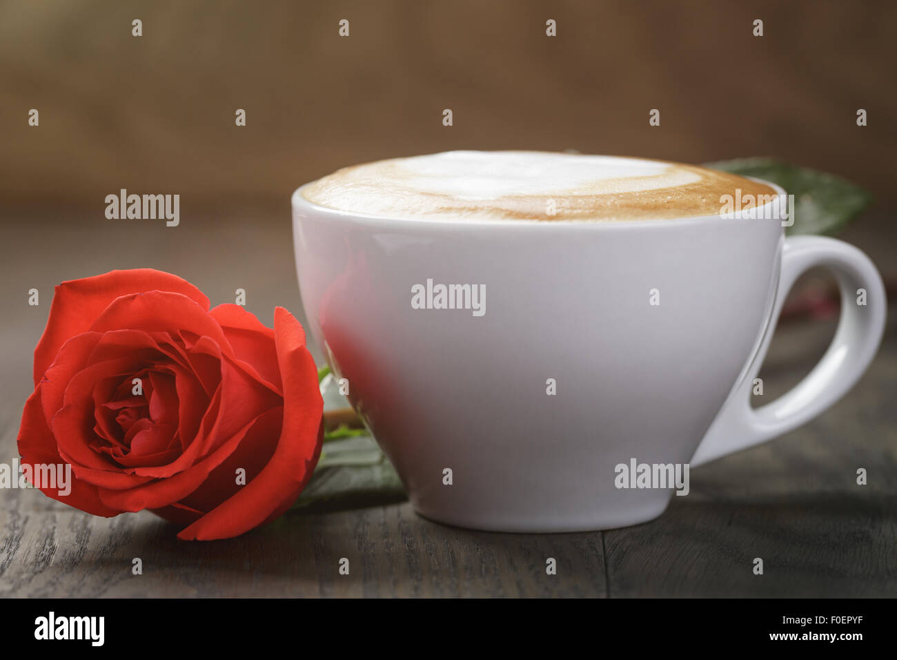 frischen Cappuccino mit roten Rose auf Holztisch Stockfoto