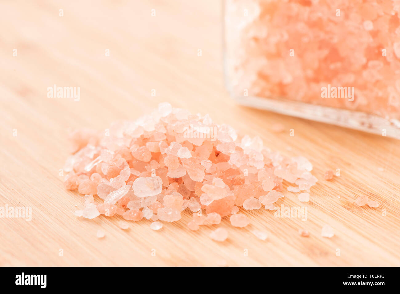 Nahaufnahme von Himalaya-Salz auf Holztisch. Food-Stillleben mit Glas im Hintergrund. Stockfoto