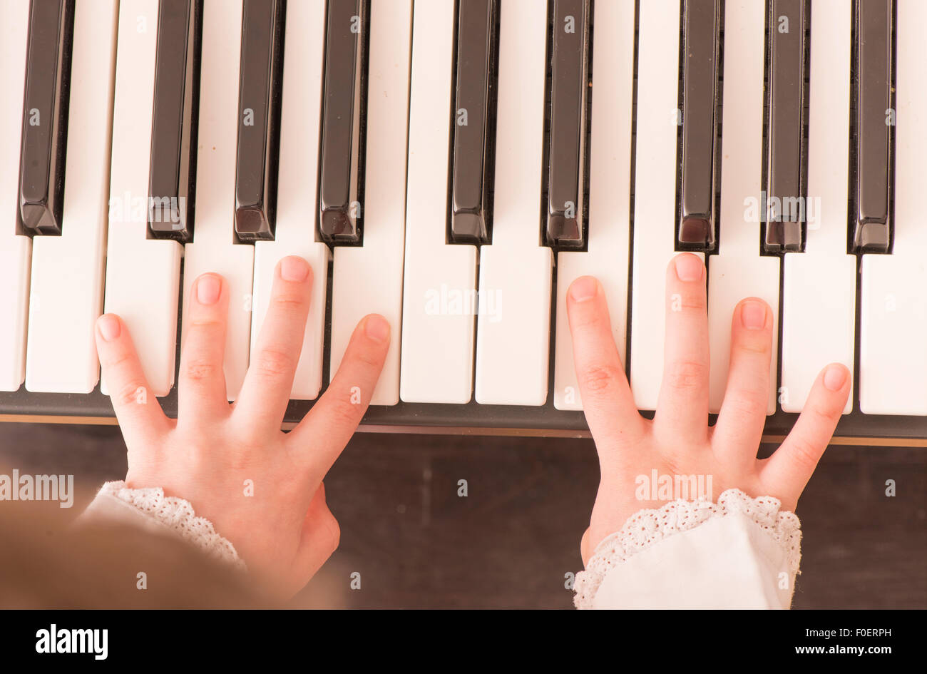 Nahaufnahme der Hände des Kindes mit dem Klavierspiel. Draufsicht von kleinen Mädchen üben auf ihre Musik. Stockfoto