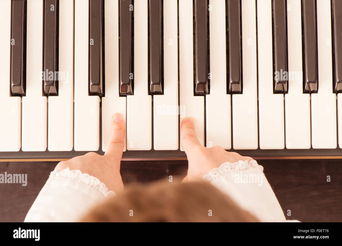 Nahaufnahme der Hände des Kindes mit dem Klavierspiel. Draufsicht von kleinen Mädchen üben auf ihre Musik. Sie nutzt nur zwei Finger. Stockfoto