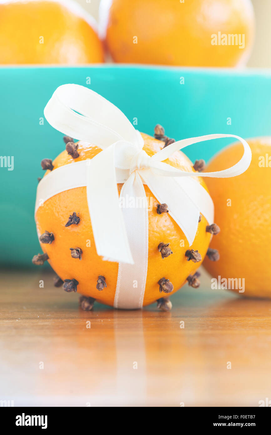 Orange mit Nelken durchbohrt und mit einem Seidenband als Bestandteil einer traditionellen Weihnachtsschmuck dekoriert. Stockfoto