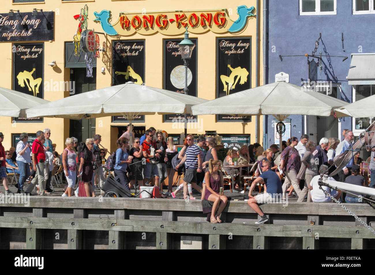 In gemütlichem Ambiente im bezaubernden Nyhavn treffen sich die Menschen und unterhalten sich über einen Drink in der Sonne. Viele sitzen lieber auf der Wharf unter den alten Schiffen. Dänische Hyge. Stockfoto